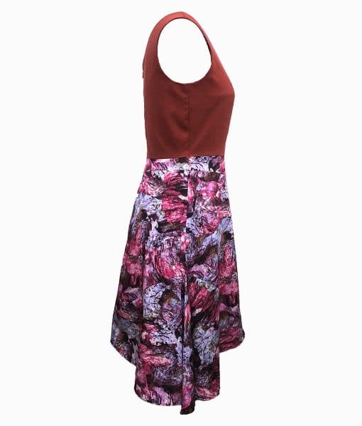 Side view of dress with a burnt orange top above the waist and wookey hole cave print skirt that is asymmetrically longer on the left side.
